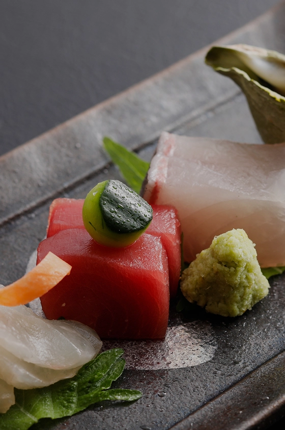 シックな黒い器に美しく盛り付けられた、新鮮で艶やかなマグロや白身魚のお造り。