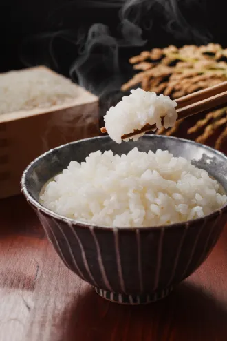 茶碗に盛られた炊きたてのご飯と、箸で持ち上げられた湯気立つ一口。