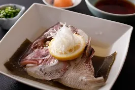 白い角鉢に昆布と盛り付けられた、鯛の酒蒸し レモンと白髪ネギ添え。