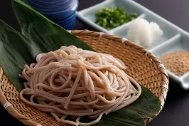 竹ざるに盛られたもち麦そば、そばつゆと薬味添え。