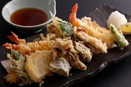 黒い和食器に盛られた、海老や旬の野菜の天ぷら盛り合わせ。