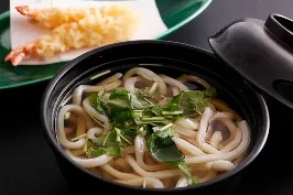 黒い椀に入った温かい素うどんと、別皿に添えられた海老の天ぷら2本。