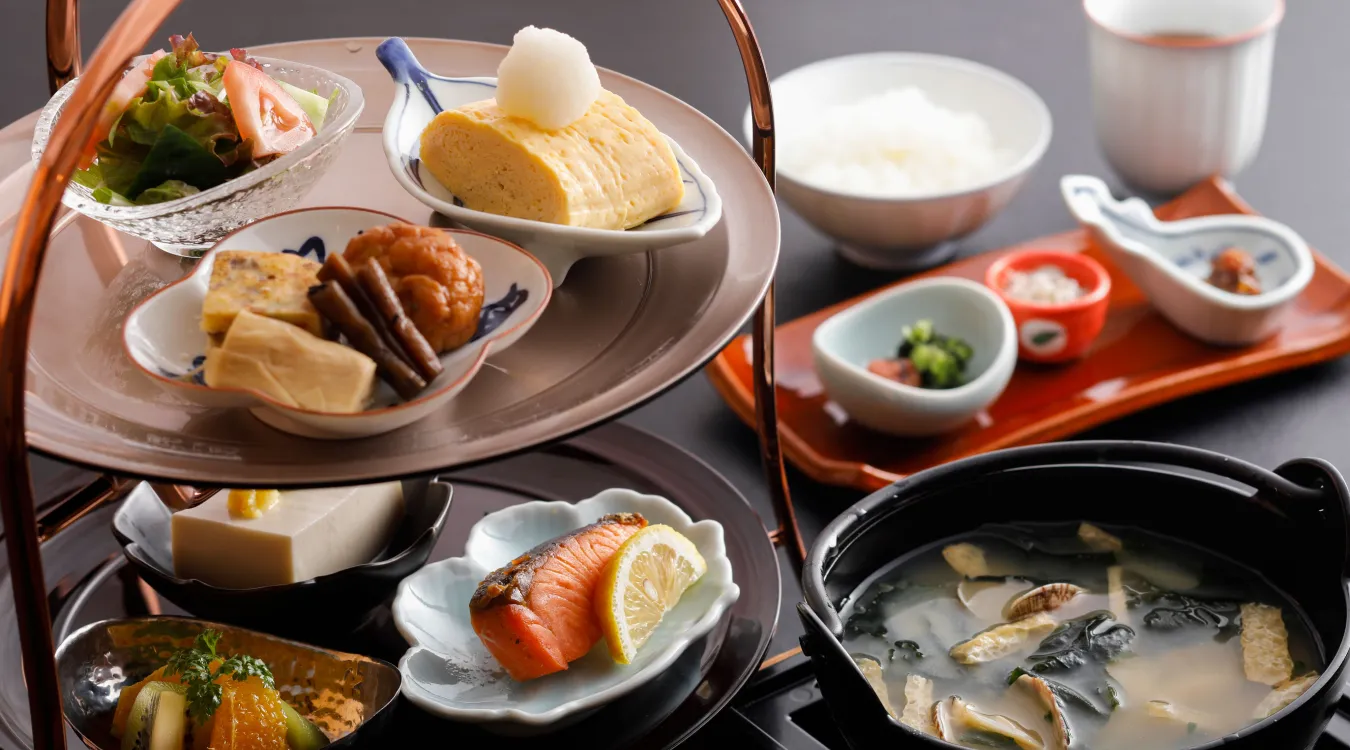 Traditional Japanese breakfast spread featuring rolled omelet, grilled fish, miso soup, and freshly cooked rice.
